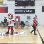 York Lion mascot with faculty members on the gym floor