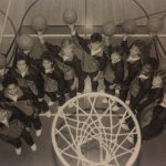 An old photo of Female basketball players holding basketballs under the net