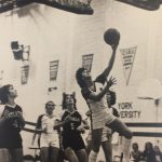 An old photo of a female basketball player doing a layup