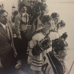 An old photo of a male hockey team watching the game
