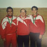An old photo of two atheltes with their coach