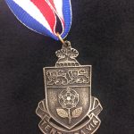 A photo of a medal that says \"Tentanda Via\"