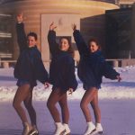 A photo of three figure skaters posing on the York University ice rink in front of Vari Hall