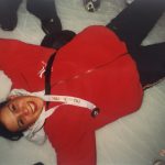 A female figure skater lying on the ice rink, smiling
