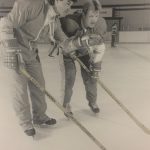 An old photo of a male hockey player being coached