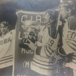 An old photo of three hockey players holding a trophy