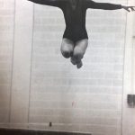 An old photo of a female gymnast jumping on a balance beam