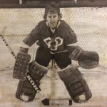 An old photo of a female hockey goalie posing with their medal on