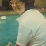An old photo of a woman in glasses at a swimming pool