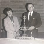 An old photo of two men and a trophy at a banquet