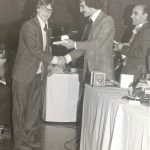 An old photo of men shaking hands at a banquet
