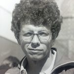 An old photo of a man with curly hair and wearing glasses