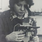 An old photo of a woman looking through a microscope