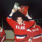 A York hockey player holding a trophy above his head