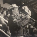 A man with his trumpet in stadium seating