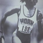 An old photo of a female runner holding a baton in a relay race
