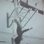 An old photo of a female gymnastics athlete doing a backwards jump on a balance beam
