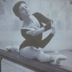 An old photo of a female gymnastics athlete doing a pose on a balance beam
