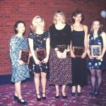 Photo of female students in formal garments holding their awards