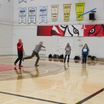 The head referee demonstrating an activity to student throwing a noodle stick