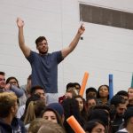 A student standing up with their hands up among the crowd of students