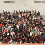 A group photo of students in the indoor gym seating