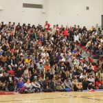 A group photo of students in the indoor gym seating