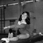 Sharon Tsukamoto in her Canadian Olympic Team uniform, doing a split atop a balance beam