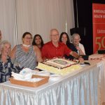 A couple event participants seated around the table with the 50th anniversary cake