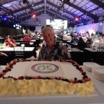 An elderly woman smiling behind the 50th anniversary cake